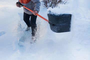 Man clearing snow by shovel after snowfall. Outdoors.