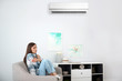 © New Africa - Young woman suffering from cold at home. Air conditioner malfunction