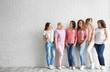 © New Africa - Group of women with silk ribbons near brick wall, space for text. Breast cancer awareness concept
