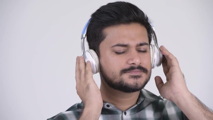 Wall Mural - Portrait of young bearded Indian man listening to music