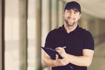 Wall Mural - Delivery man with clipboard on office background