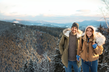 Happy couple spending winter vacation together in mountains. Space for text