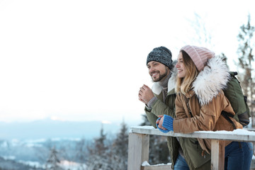 Couple with backpacks enjoying mountain view during winter vacation. Space for text