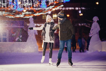Winter Skates, Loving Couple Holding Hands And Rolling On Rink. Illumination In Background, Night. Concept Training