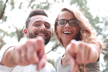 close up.happy newlyweds standing in the Park and pointing at you