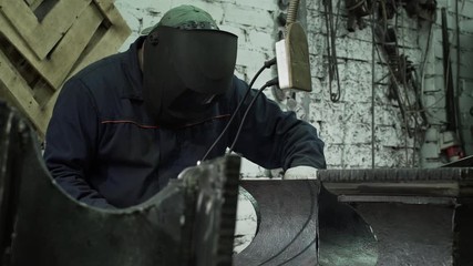 Wall Mural - Middle-aged Man A Blacksmith In Protective Clothing Connects The Two Sides