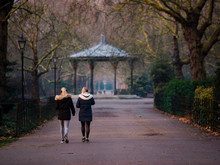 Battersea Park's Ornate Victorian Bandstand In Golden Hour, With Two Women Walking Towards It
