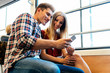 © santypan - Portrait of young couple using mobile phone in the street.