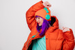© Masson - Beautiful young girl with purple hair and in orange jacket listen music in headphones on white background.