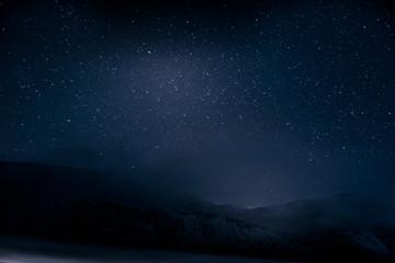 beautiful blue dark night sky with many stars above snowy mountains