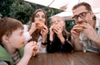© ASDF - hungry family eating hamburgers, sitting at a table in a fast food restaurant