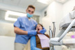 © PhotoSpirit - Dentist performing teeth treatment with female patient blurred, focus on tools