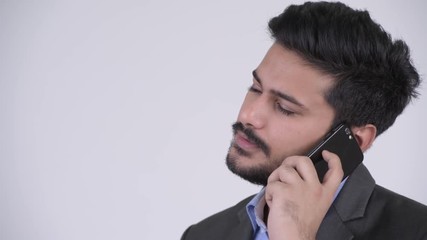 Wall Mural - Young bearded Indian businessman talking on the phone