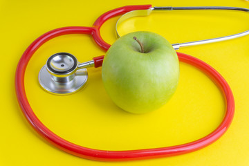 Wall Mural - Green Apple with medical stethoscope isolated on yellow background for healthy eating. Selective focus and crop fragment. Healthy, Diet and copy space concept