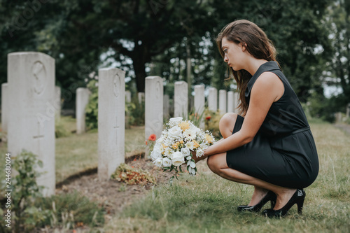 Fotografía Young widow laying flowers at the grave