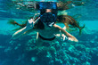 © F8  \ Suport Ukraine - Young woman snorkeling making peace signs underwater near coral reef