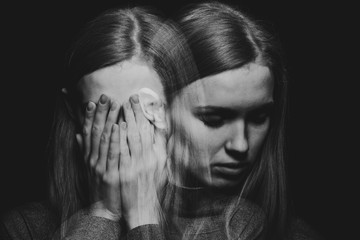 Black and white porter of beautiful redhead girl with psychotic disorders covering her face, hiding from her hallucinations