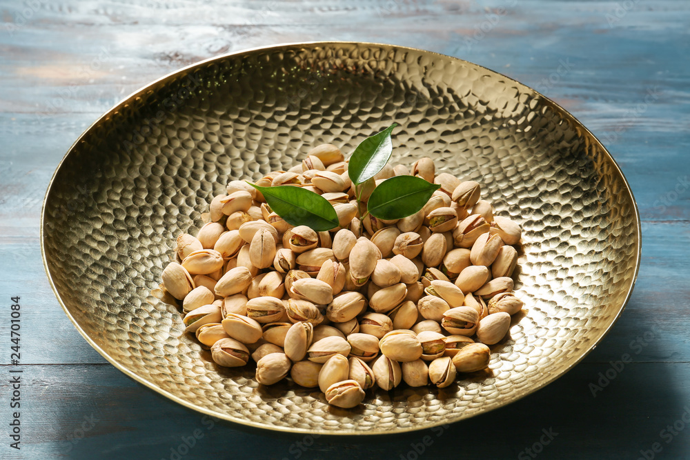 Bowl with tasty pistachio nuts on table