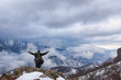 © Ivan - Hiker standing on a mountain top and looking into dynamic sky. Foggy mountain, Colorful winter landscape