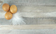 Brown chicken eggs with feather at wooden background