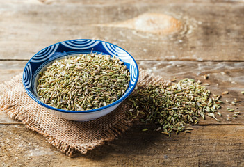 Fennel seeds in a bowl on wood background,