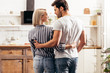 © LIGHTFIELD STUDIOS - selective focus of handsome boyfriend and attractive girlfriend hugging and standing in kitchen