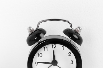 Black vintage alarm clock on a white background close up