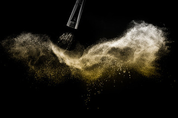 Wall Mural - Cosmetic brush with golden cosmetic powder spreading for makeup artist and graphic design in black background