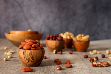 Wall Mural - Hazelnuts, cashews, Brazil nuts and almond wooden bowls on a gray background.