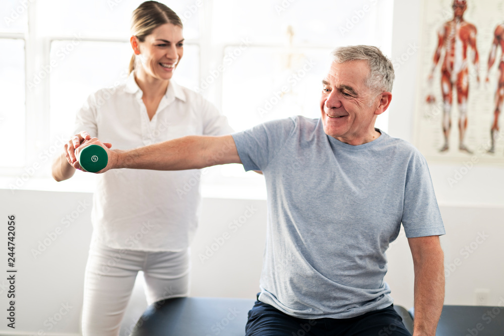 A Modern rehabilitation physiotherapy worker with senior client - obrazy, fototapety, plakaty 