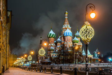 Vasilevsky descent in the winter snowy night. Illuminated Saint Basil`s Cathedral, Kremlin wall and Middle lines on Red Square in Moscow.