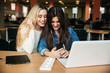 © Aleksandr - Two girl student use tablet and laptop in library. And listen music