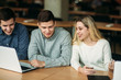 © Aleksandr - Group of college students studying in the school library, a girl and a boy are using a laptop and connecting to internet. Prepare for an exam