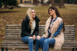 © Aleksandr - Two girls sitting on the bench outdoors. Autumn weather