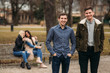 © Aleksandr - Young people having a good time in park. Male and female sitting on the bench and using phones