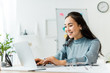 © LIGHTFIELD STUDIOS - beautiful smiling asian businesswoman sitting at desk and using laptop in office
