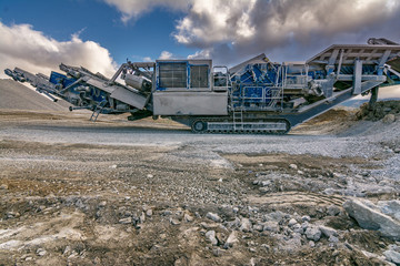 Stone crusher machine in a quarry or open-pit mine, to transform into gravel