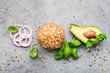 Ingredients for making healthy vegetarian avocado burger with basil, red onion, avocado on cereal buns. Gray light background. Top view, space.