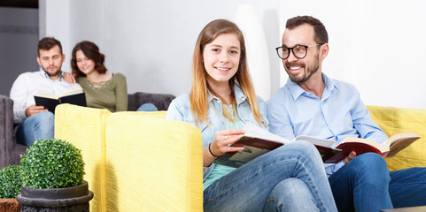 Wall Mural - Positive young man and woman resting with books in cozy hostel lobby