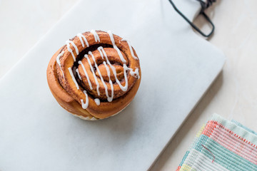 Homemade Fresh Cinnamon Roll / Bun with Cream Sauce served with Marble Board.