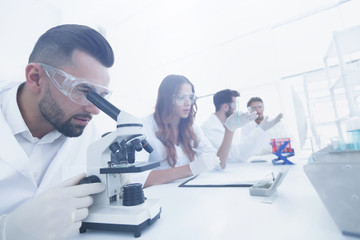Wall Mural - male laboratory technician looking at samples in the microscope