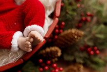 The Steps Of A Newborn Baby On A Background With Christmas Decorations.  Little Santa 