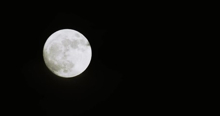 Wall Mural - Full moon against dark black sky with partial clouds
