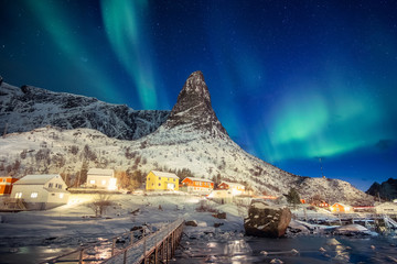 Wall Mural - colorful scandinavian village with northern lights over peak mountain at lofoten