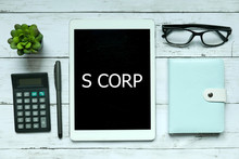 Business Concept. Top View Of Plant,calculator,glasses,pen,notebook And Tablet Written With S Corp On White Wooden Background.