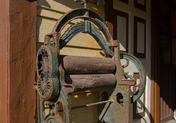 Antique rolling machine in front of house. Old equipment used to dry clothes by passing them between two rollers that press the water from the material