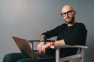 Wall Mural - Modern young caucasian man with beard and glasses relaxing while surfing internet on laptop pc