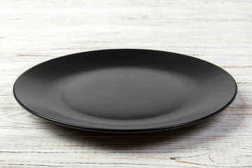 Perspective view. Empty dark matte dish for dinner on white wooden background