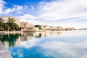 Ortigia, Syracuse, Italy / December 2018: Coast of Ortigia island at city of Syracuse. Long exposure sea. Reflection in water. Landscape reflection in sea