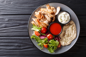 Mediterranean Chicken Shawarma Bowl with hummus, vegetables salad and sauce close-up. Horizontal top view